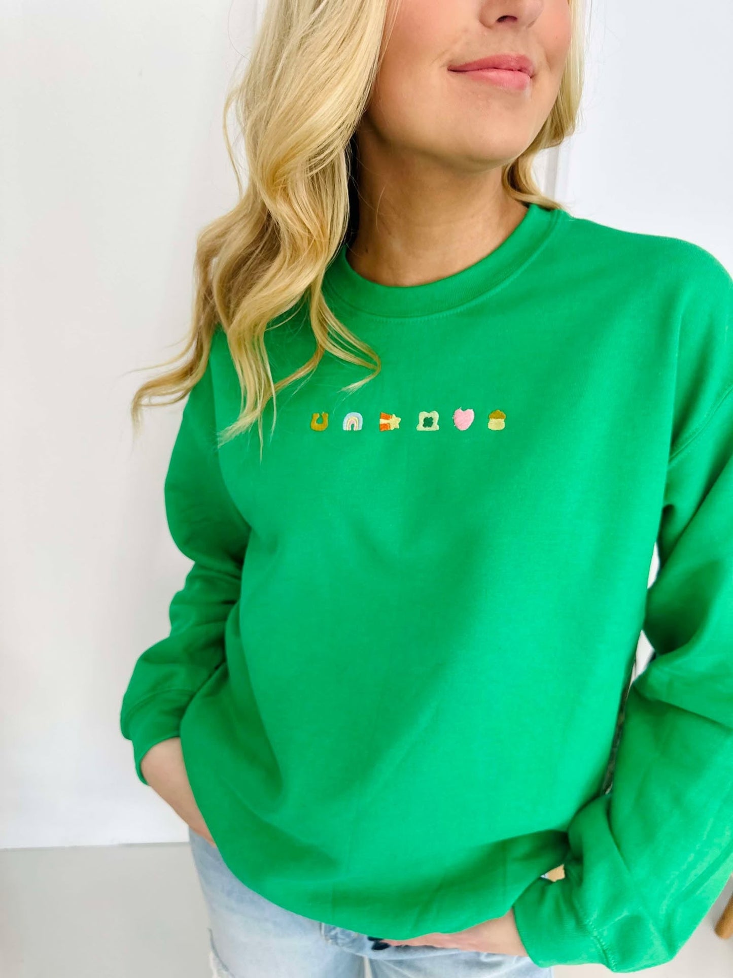 A woman wearing a green embroidered sweatshirt with decorative elements on the front.