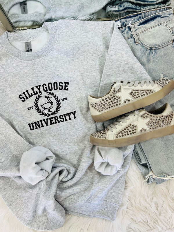 A gray embroidered sweatshirt with 'Silly Goose University' text on the front, paired with white sneakers with embellishments on the sole.
