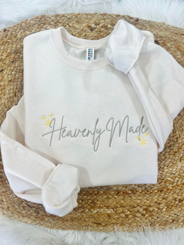 White sweatshirt with 'Heavenly Made' text on a woven surface