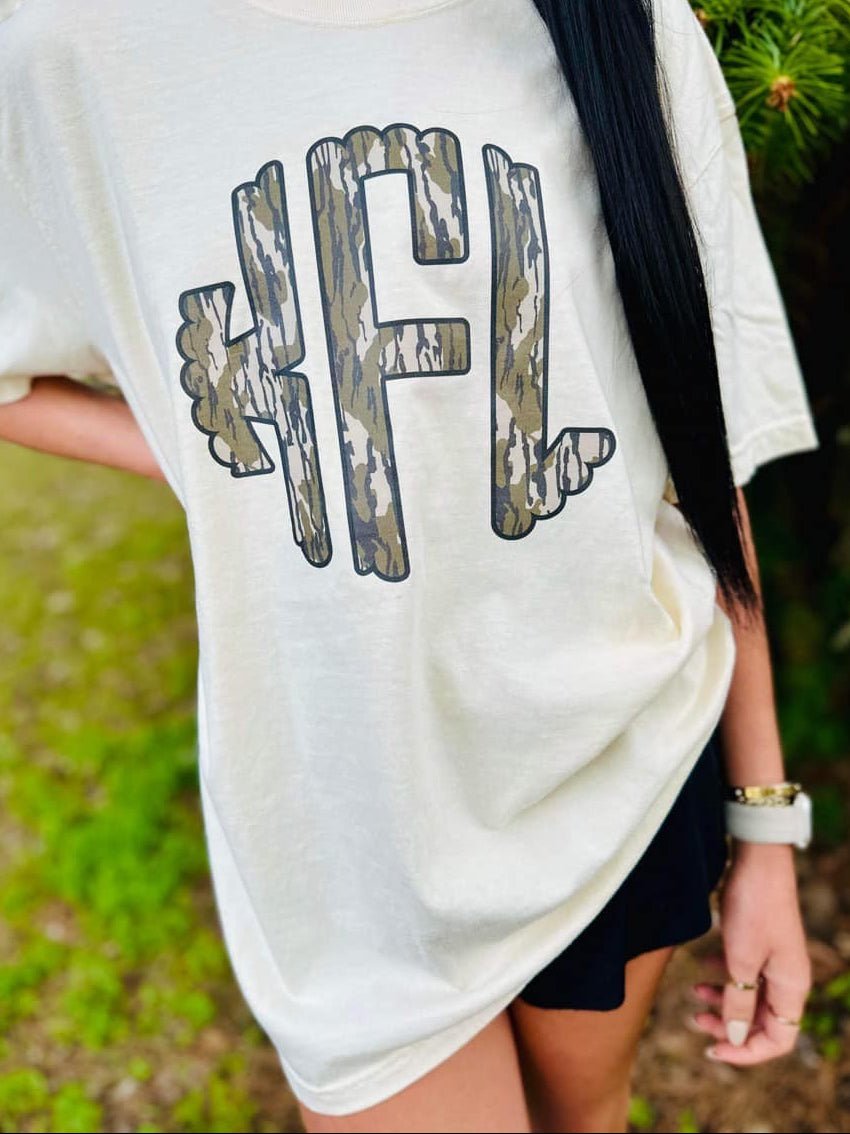 Person wearing a Ivory t-shirt with a Mossy Oak Bottomland graphic design outdoors