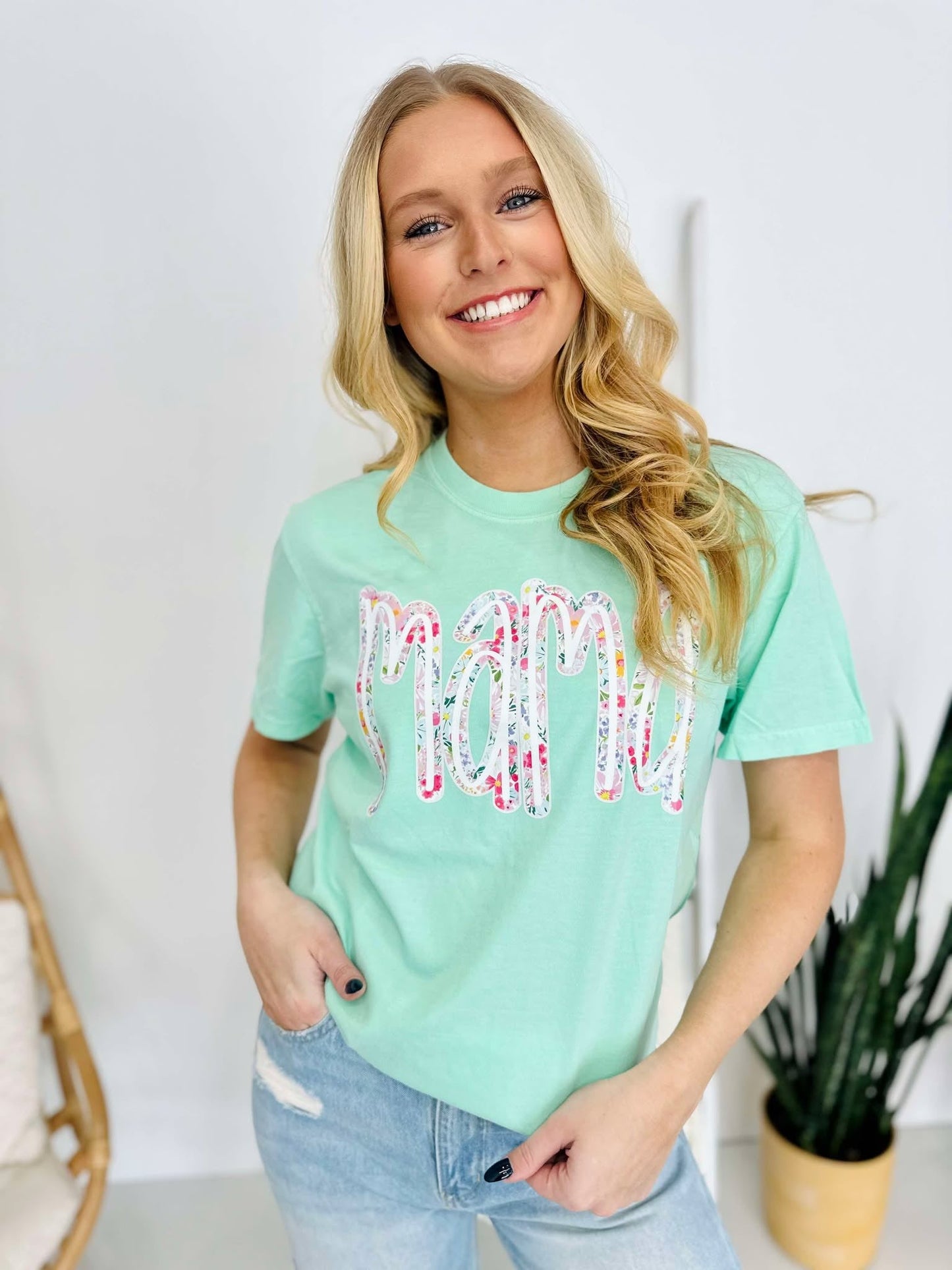 A woman smiling and wearing a green t-shirt with a multicolored floral farm DTF print.