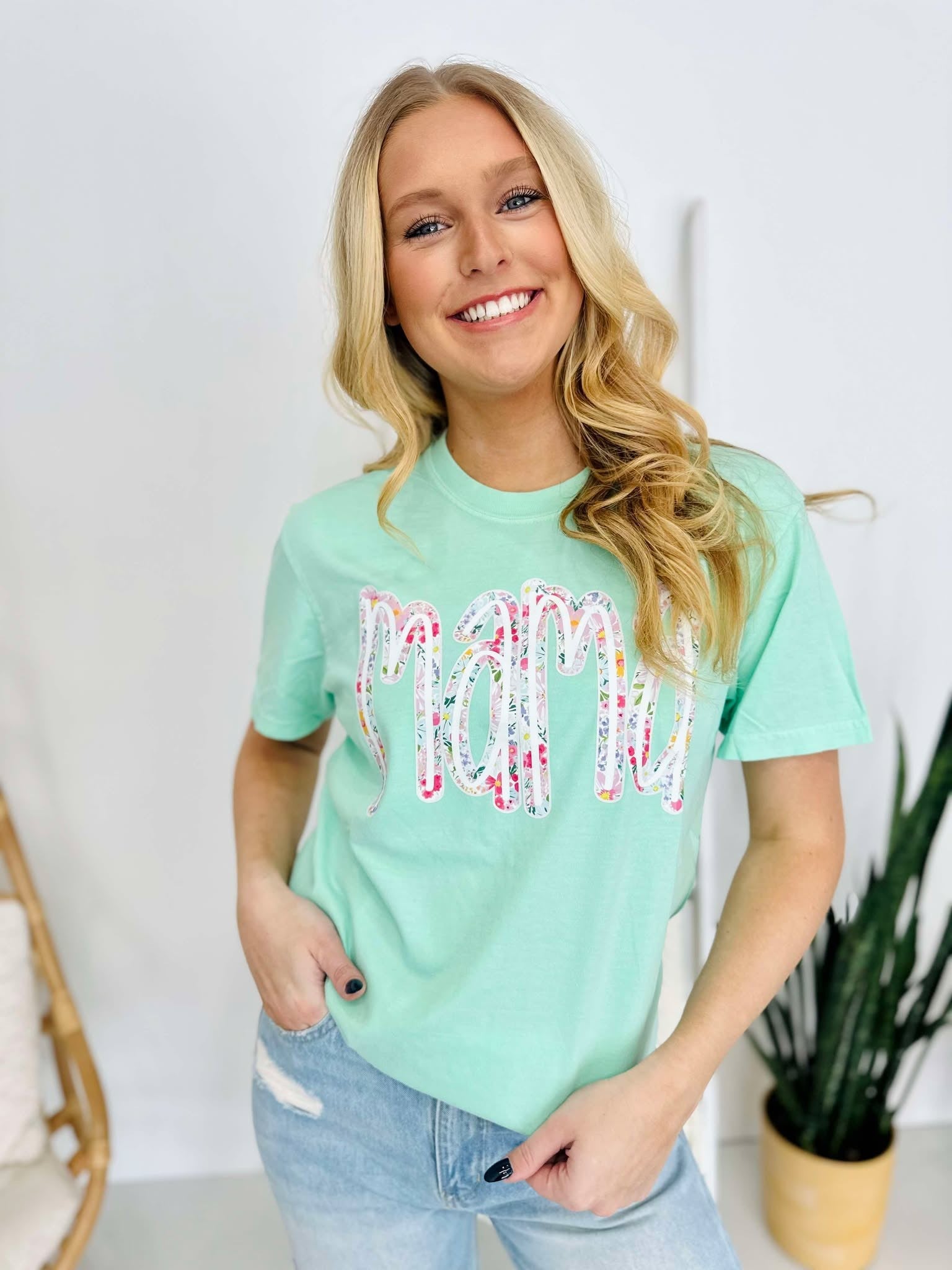 A woman smiling and wearing a green t-shirt with a multicolored floral farm DTF print.