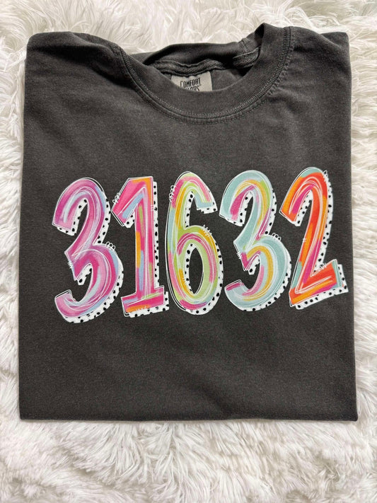 A folded black t-shirt with the zip code '31632' painted in various colors on the front.