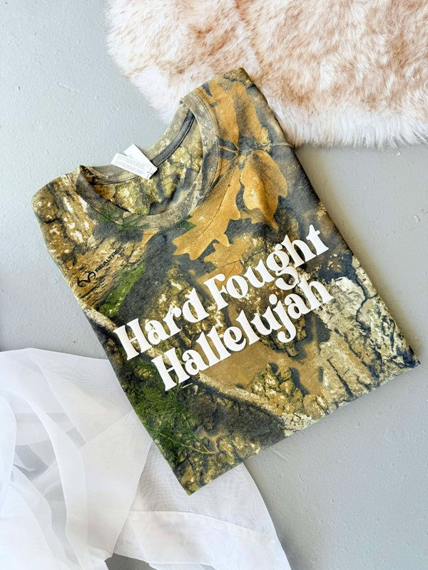 A Real Tree camouflage graphic tee with the text 'Hard Fought Hallelujah' printed in white vinyl on the front.