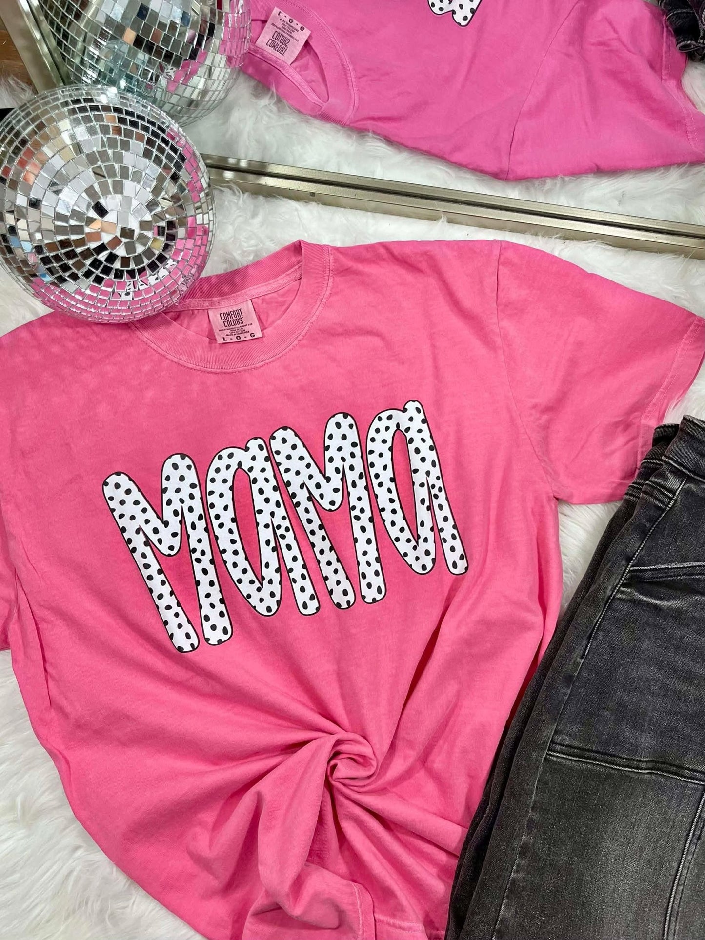 Pink t-shirt with 'MAMA' printed in polka dots, disco ball, and jeans in the background