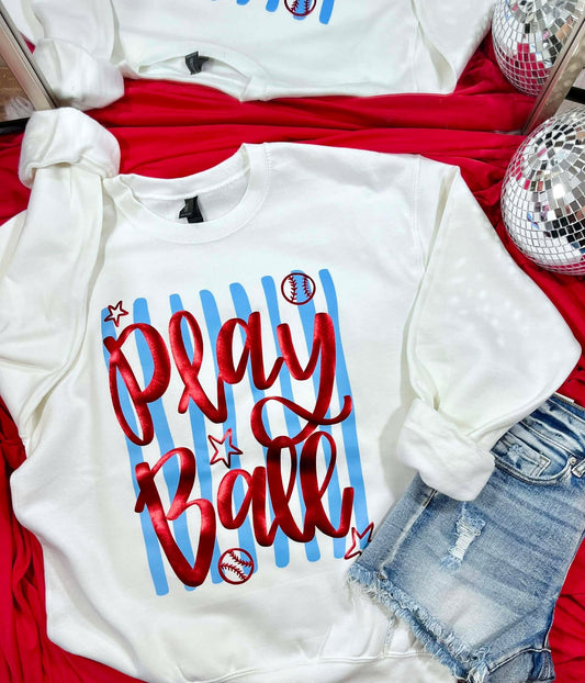 White sweatshirt with 'Play Ball' text on a red surface with denim shorts and disco balls.