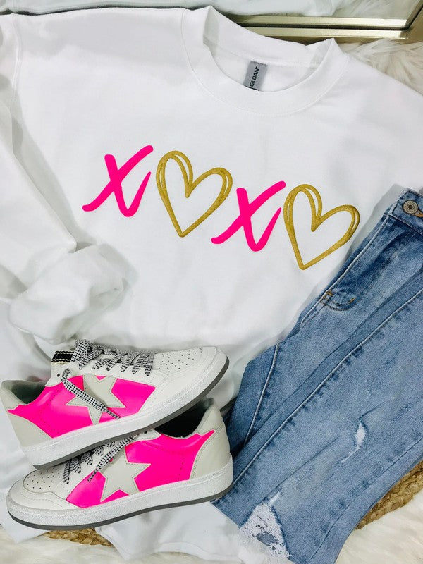 A white sweatshirt with 'XOXO' and heart vinyl designs, paired with blue denim jeans and white sneakers with pink accents.