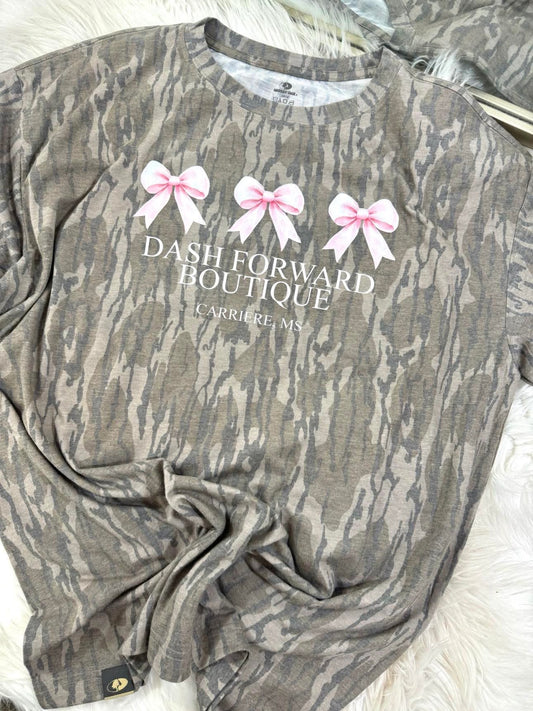 Mossy Oak Camouflage shirt with 'Dash Forward Boutique' text and pink bows on a white surface