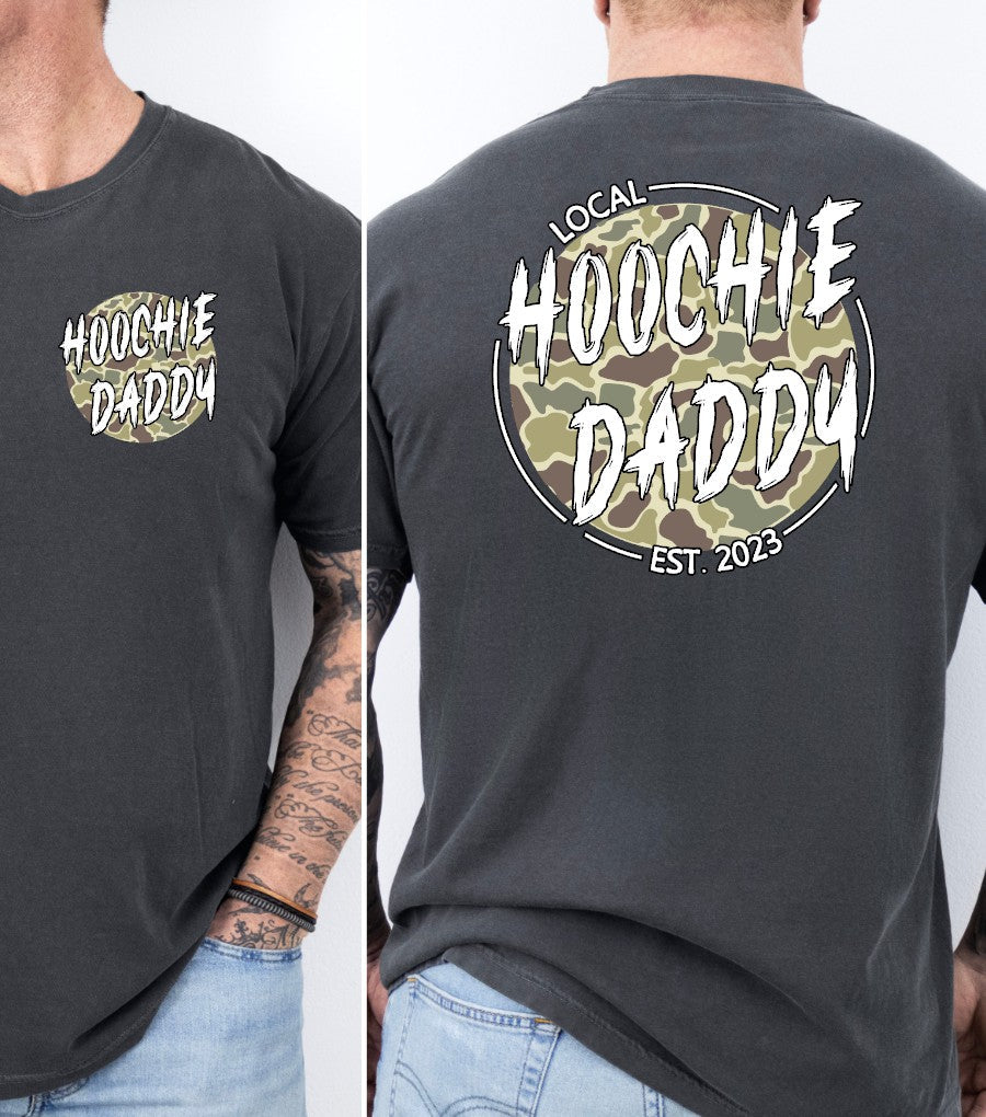 A graphic tee with 'HOOCHIE DADDY' printed on the front and a camouflage pattern on the back, available in a color named 'Pepper'.